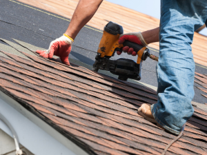 A professional roofer installing new shingles on a residential roof.